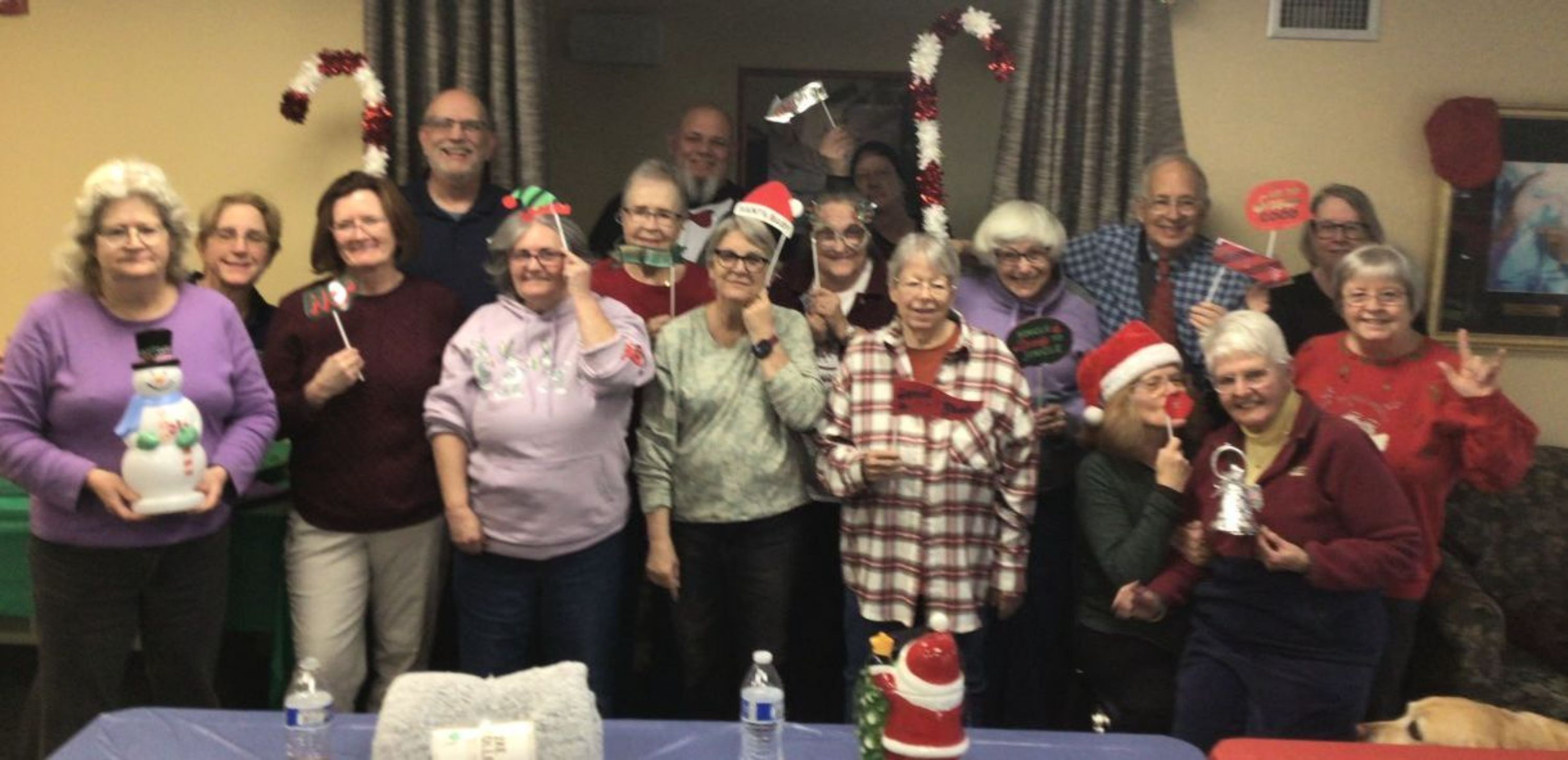 Image of happy people in festive attire standing in back of a table with festive decorations.
