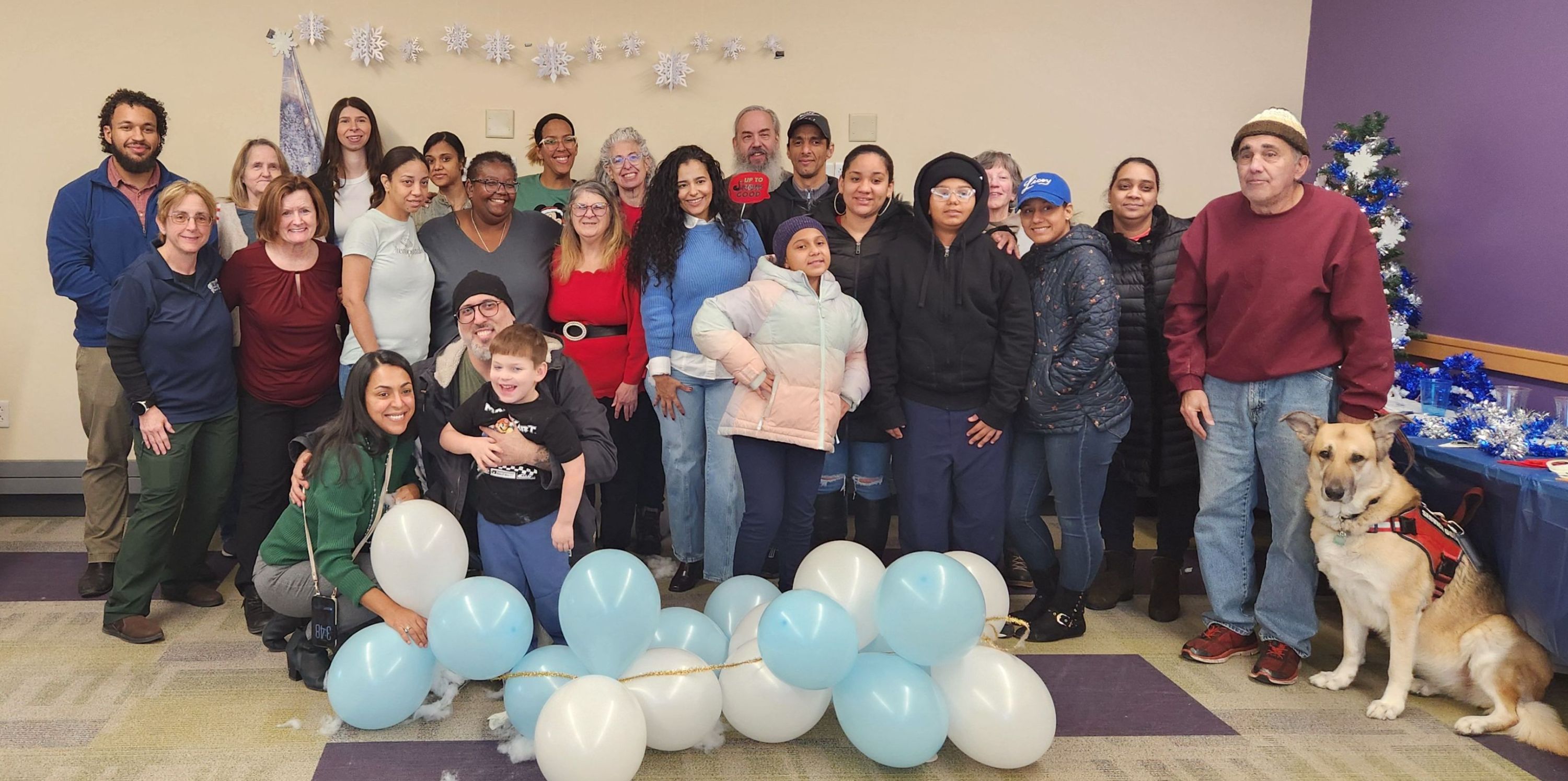 Image of happy people in festive attire standing in front of wall with balloons in front. American flag on left side..