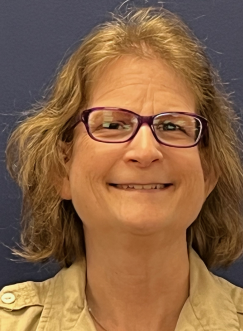 Image description: Liz Olson, Advocate, a white woman with medium-length dirty blonde hair, wearing glasses and a beige shirt, smiling. Image description: Liz Olson, Advocate, a white woman with medium-length dirty blonde hair, wearing glasses and a beige shirt, smiling.
