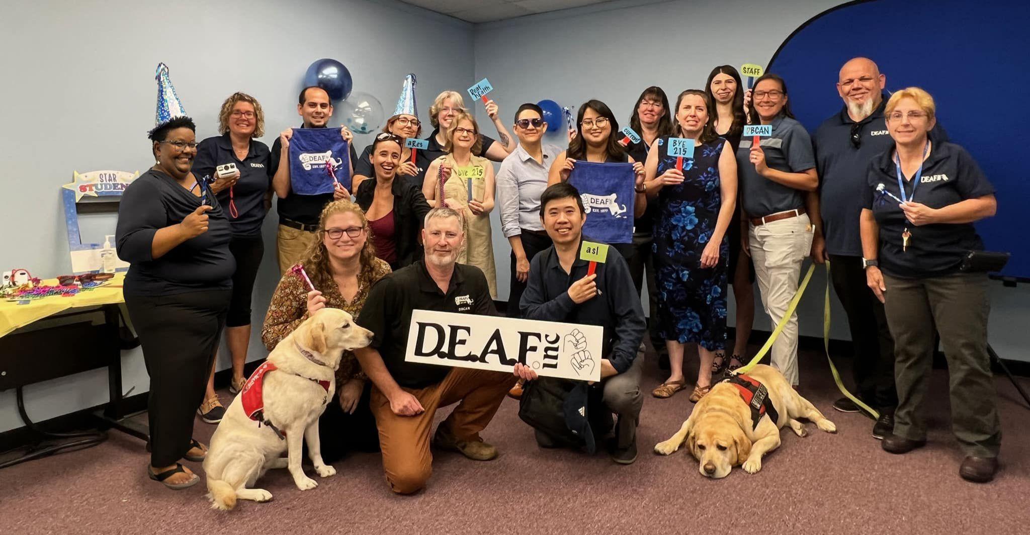 A group photo of smiling DEAF, Inc. staff, directors, advocates, and service dogs at the Farewell 215 party.