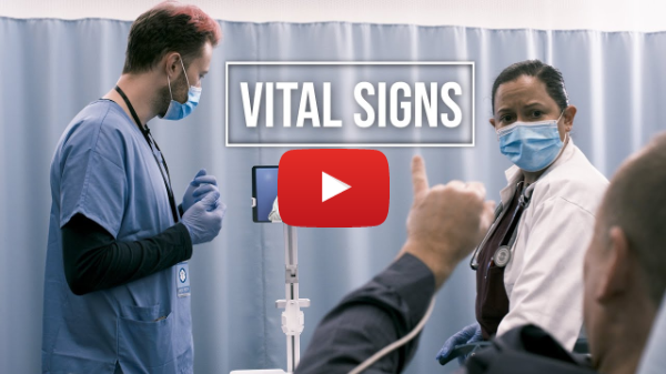 A video thumbnail of a hospital setting. A doctor and a nurse both in a blue mask are standing in front of a person signing in the lower right corner. A white outlined box with “VITAL SIGNS” are in the middle above a red Youtube play button.