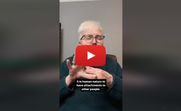 A YouTube video still image of a person in a green sweater and white hair and black glasses signing. The text under them reads, “It is human nature to have attachments to other people.”