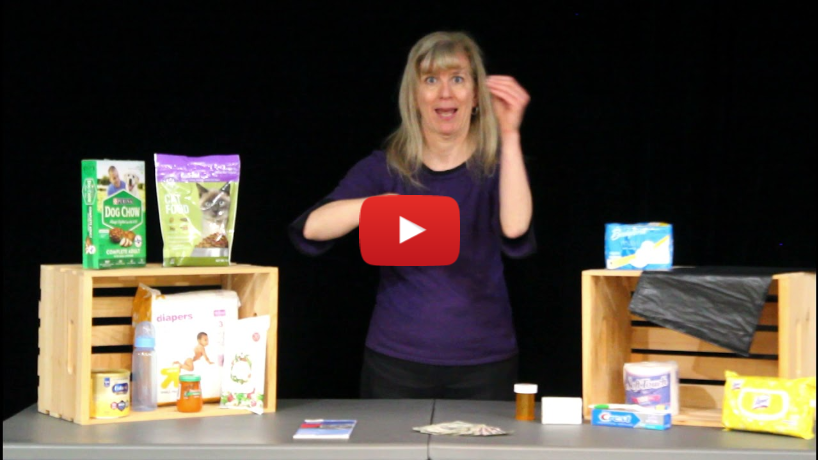 Emergency Preparedness: Emergency Backpack - A still frame from a video featuring a woman standing behind a table, using American Sign Language (ASL) to communicate. The table is set up with various items that appear to be part of an emergency preparedness kit. Key Elements: The Woman: She has shoulder-length blonde hair and is wearing a purple shirt. She is using ASL to provide information, likely about the items on the table and their importance in an emergency kit. Items on the Table: Left Side: Pet food (bags of dog food). Baby items such as a bottle, a jar of baby food, and a pack of diapers. Right Side: Hygiene items including toilet paper, sanitary pads, a pack of baby wipes, and a black trash bag. Center: Small items such as a medicine bottle, some cash, and a pamphlet. Setup: The items are organized in and around wooden crates, likely to display them clearly for the video audience. Background: The background is black, which helps to highlight the speaker and the items on the table. Play Button: A large red play button with a YouTube logo is overlaid on the image, indicating that this is a screenshot from a video,