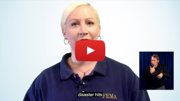 Personal Disaster Preparedness: I Am Hard of Hearing - A still frame from a video featuring a woman who appears to be delivering an important message. She is wearing a navy blue shirt with the FEMA (Federal Emergency Management Agency) logo, indicating that she is a representative of this agency. Key Elements: The Woman: She has short blonde hair, is wearing hoop earrings, and appears to be speaking directly to the camera. She is likely delivering a message or instructions related to emergency management or disaster preparedness. Subtitle: There is a subtitle at the bottom that reads "disaster hits," suggesting the video is discussing what to do when a disaster occurs. ASL Interpreter: In the lower right corner, there is an inset showing an American Sign Language (ASL) interpreter, making the video accessible to the Deaf and Hard of Hearing community. Play Button: A large red play button with a YouTube logo is overlaid on the image